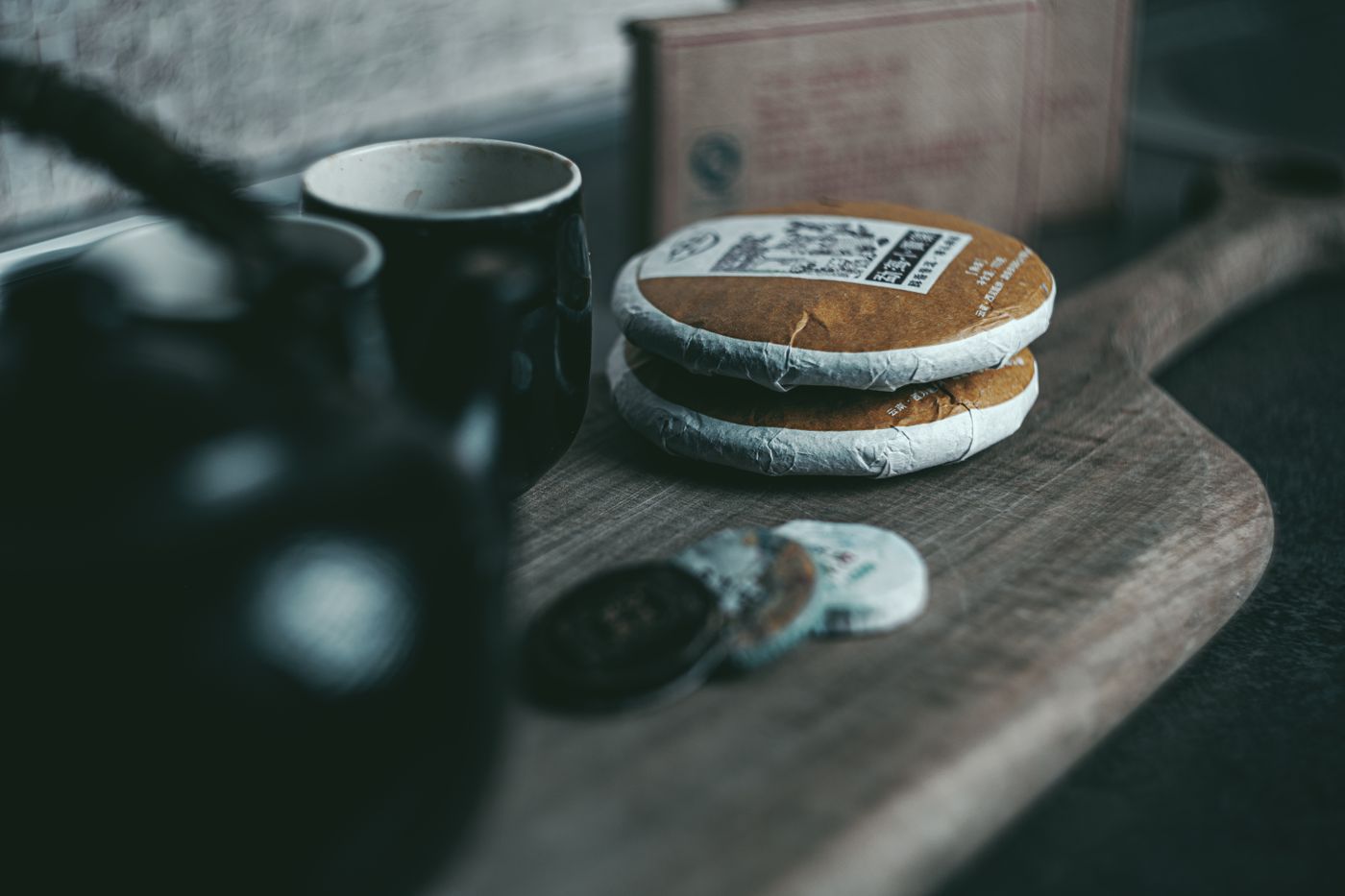 普洱茶餅與陶瓷茶壺的靜物陳設,營造傳統品茶氛圍 | Still life of puerh tea cakes and a ceramic teapot, evoking a traditional tea experience