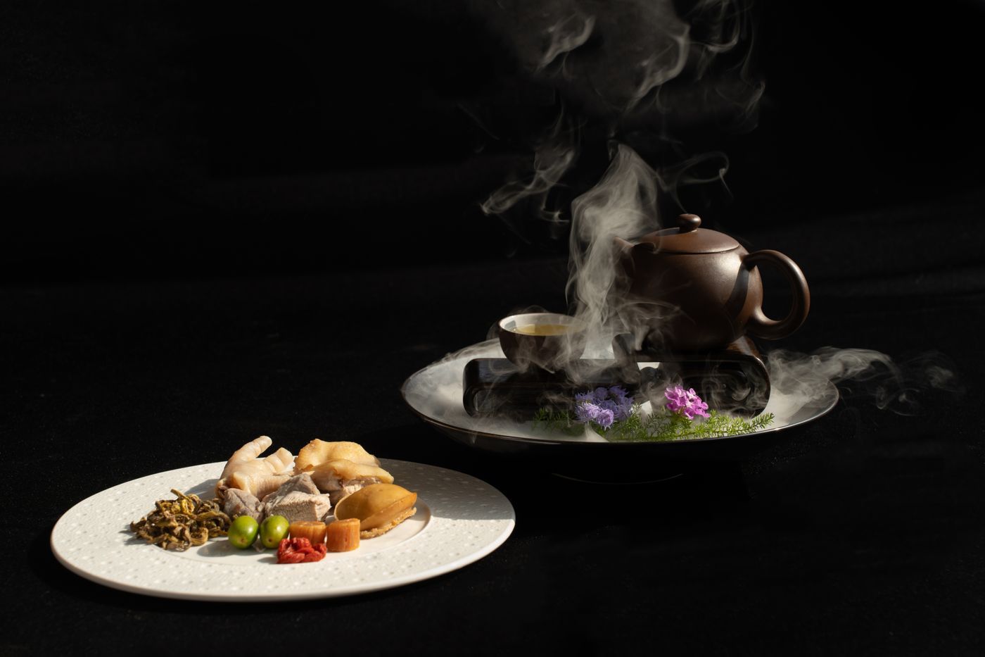 冒著熱氣的茶壺搭配亞洲菜餚,呼應茶與中式餐點搭配傳統 | Steaming teapot paired with Asian dishes, echoing the tradition of tea paired with Chinese cuisine
