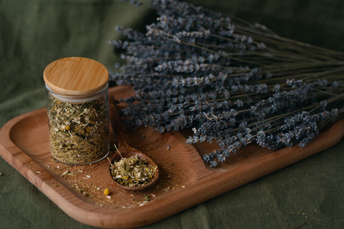 木板上陳列的乾燥薰衣草與香草罐,呈現花草茶的天然原料 | Dried lavender and herb jars arranged on a wooden board, showcasing herbal tea natural ingredients