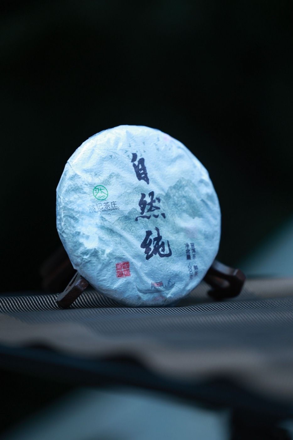 傳統包裝普洱茶餅特寫,印有漢字品牌標識,展現大益品牌文化底蘊 | Close-up of traditionally wrapped puer tea cake with Chinese characters showcasing Dayi brand heritage