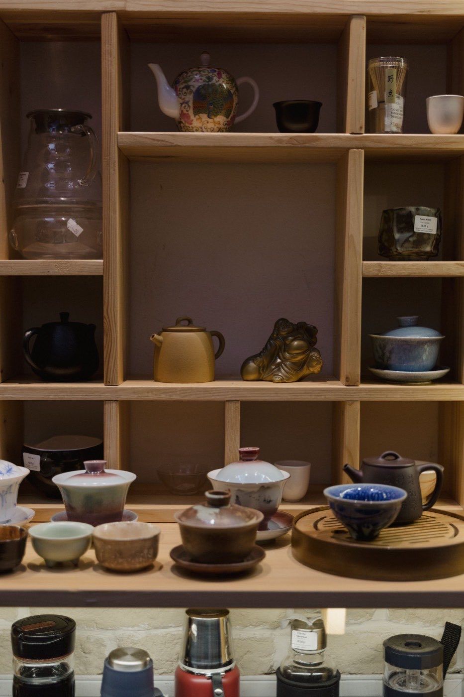 傳統茶具與器具整齊陳列於木製展示架上,呈現實體茶行選購氛圍 | Traditional tea sets and utensils neatly displayed on wooden shelves showcasing physical tea shop atmosphere