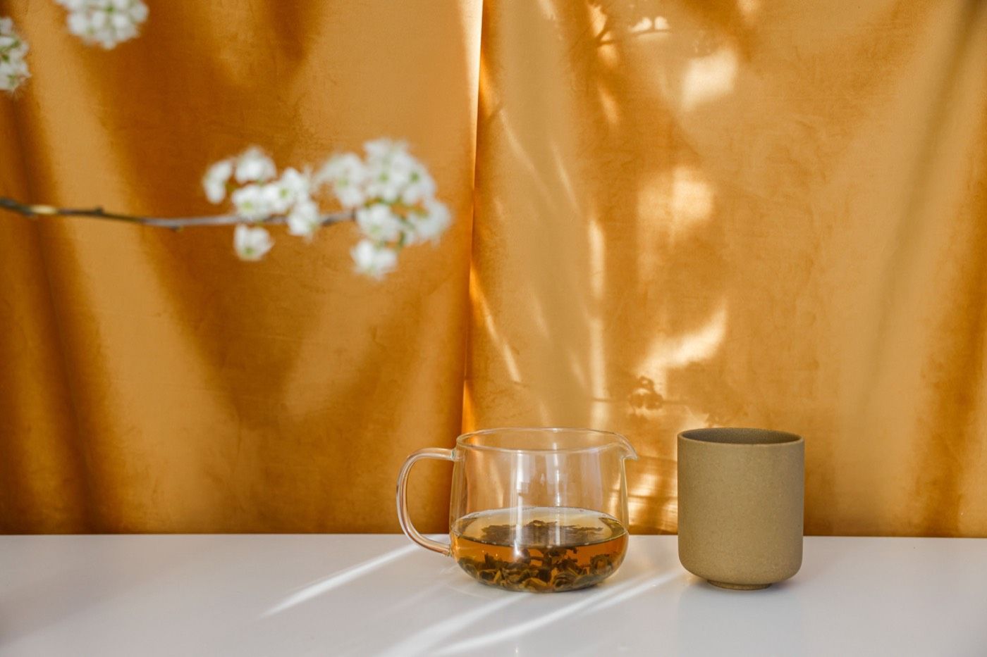 琥珀色茶湯盛於玻璃杯中,暖調光影呈現茶色層次 | Amber tea liquor in glass cup with warm lighting showcasing tea color depth