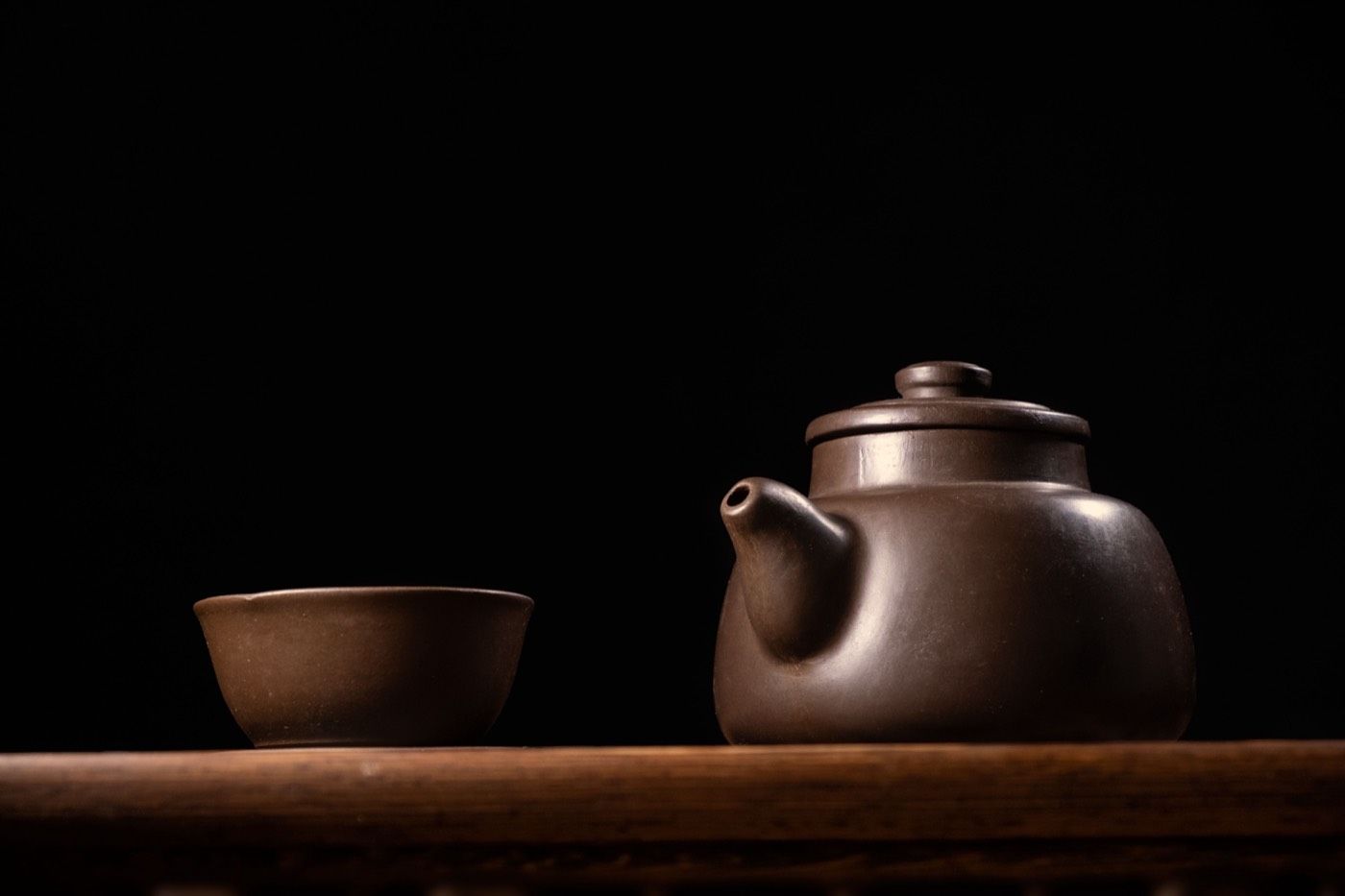 深色背景下的紫砂茶壺特寫,展現養壺後的溫潤質感 | Dark-background zisha teapot closeup showing the mellow luster from proper seasoning